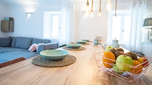 A modern living room with a wooden dining table, a sofa, and a fruit basket. - La Bastide des Bourguets (Sault)