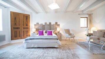 Un dormitorio espacioso con una cama grande, armario de madera, una silla moderna y un sofá.