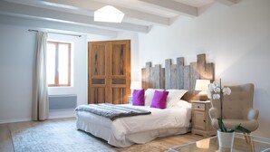 A modern bedroom with a large bed, a glass coffee table, a wooden wardrobe, and a nightstand with a lamp. - La Bastide des Bourguets (Sault)