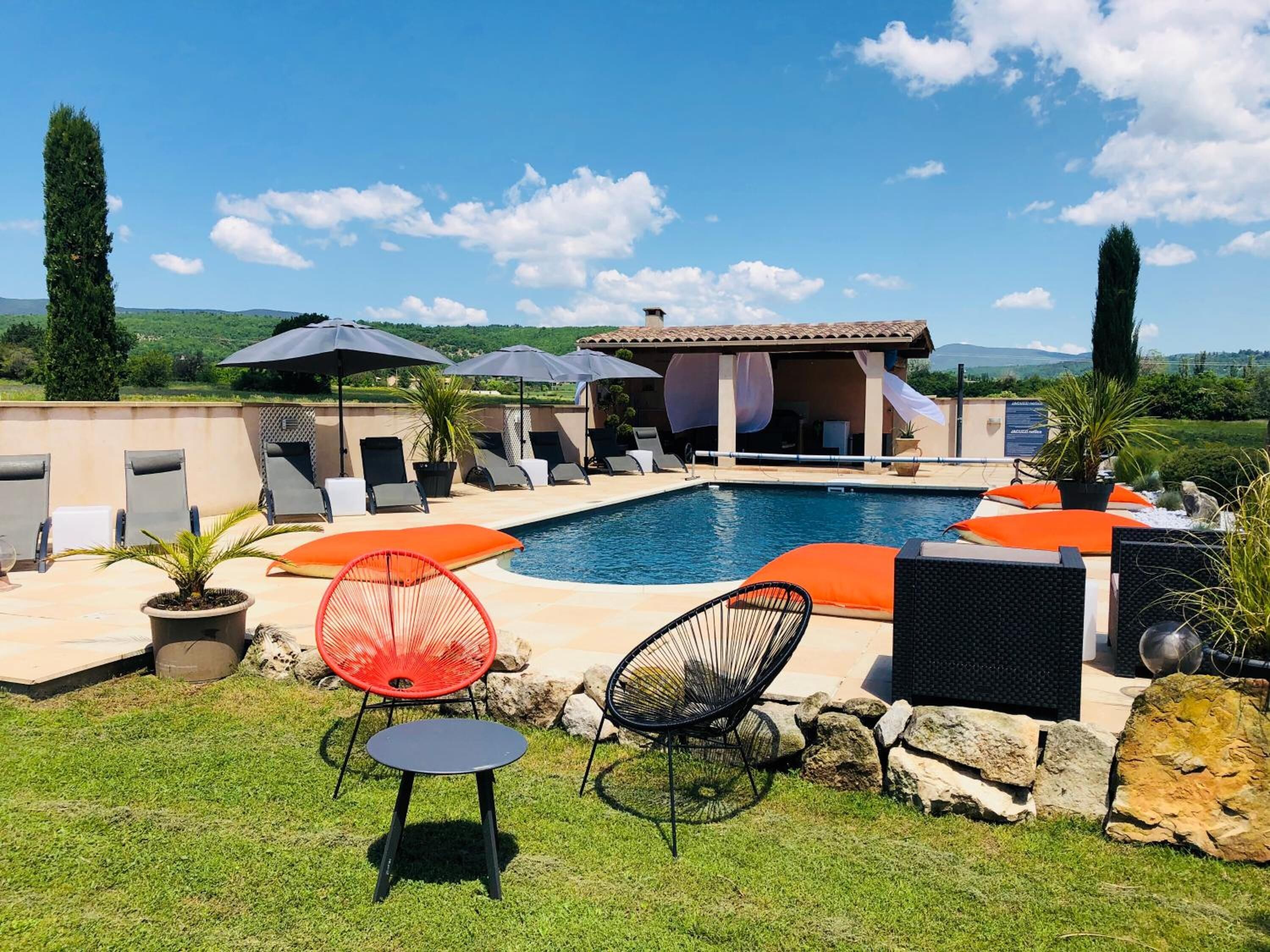 A poolside area with lounge chairs, umbrellas, and a pool.