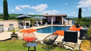 A poolside area with lounge chairs, umbrellas, and a pool.