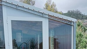 Een modern gebouw met een glazen schuifdeur, een terras met buitenmeubilair en uitzicht op het omliggende landschap.
