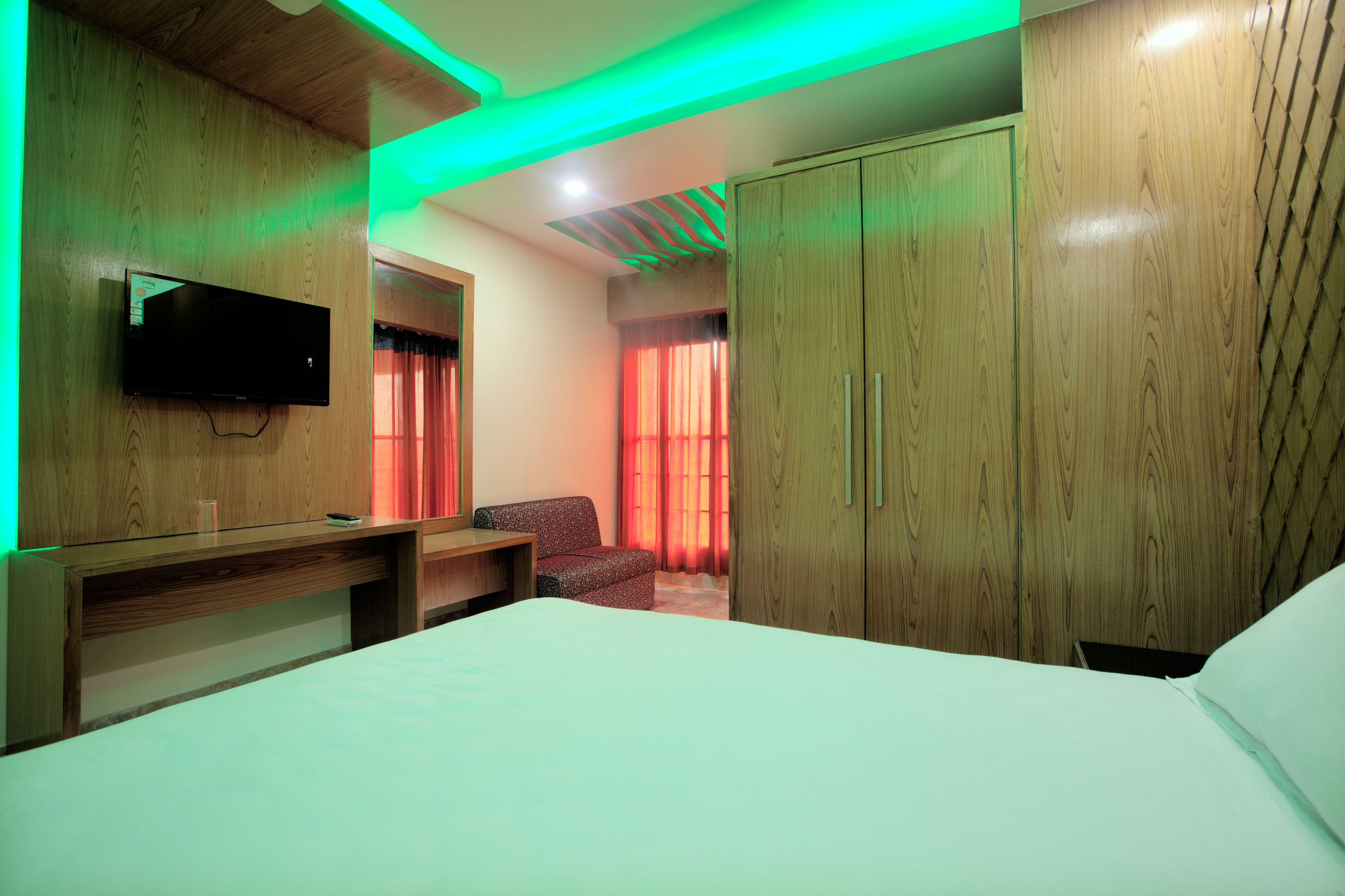 A hotel room with a bed, a desk, a TV, and a wardrobe.