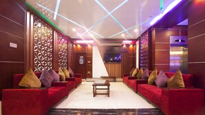 A lobby with red sofas, a coffee table, and a TV screen. - Galaxy Resort Limited (Cox's Bazar)