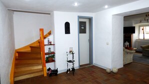 A living room with a wooden staircase, a door with a toilet sign, a television, and a small table with a plant and a decorative item. - Relaxen am Nationalpark Eifel (Blankenheim)