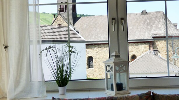 A room with a large window overlooking a building with a tower and stone walls. - Relaxen im alten Winzerhaus (Rech)