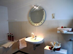 A bathroom with a round mirror, a sink, a toilet, and a shelf with a towel and a rose. - Relaxen im gemütlichen Eifelhaus (Kesseling)