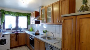 A kitchen with wooden cabinets, a washing machine, an oven, and a sink. - Relaxen im gemütlichen Eifelhaus (Kesseling)
