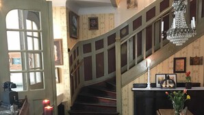 A room with a staircase, a chandelier, and a patterned floor. - Berg Säteri (Vase)