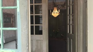 A room with a chandelier, a patterned floor, and a door leading to another room. - Berg Säteri (Vase)