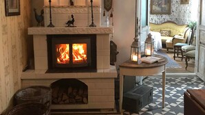 A cozy room with a fireplace, patterned floor, and a view of a living area. - Berg Säteri (Vase)