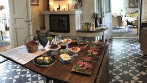 A dining table set with various food items and a fireplace in the background. - Berg Säteri (Vase)