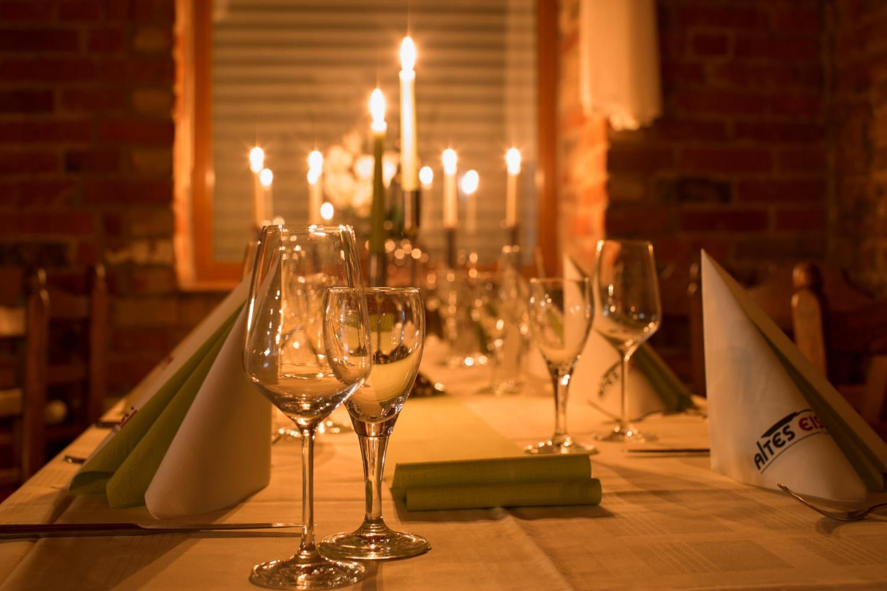 A dining table set with multiple wine glasses, a candle centerpiece, and a napkin holder.