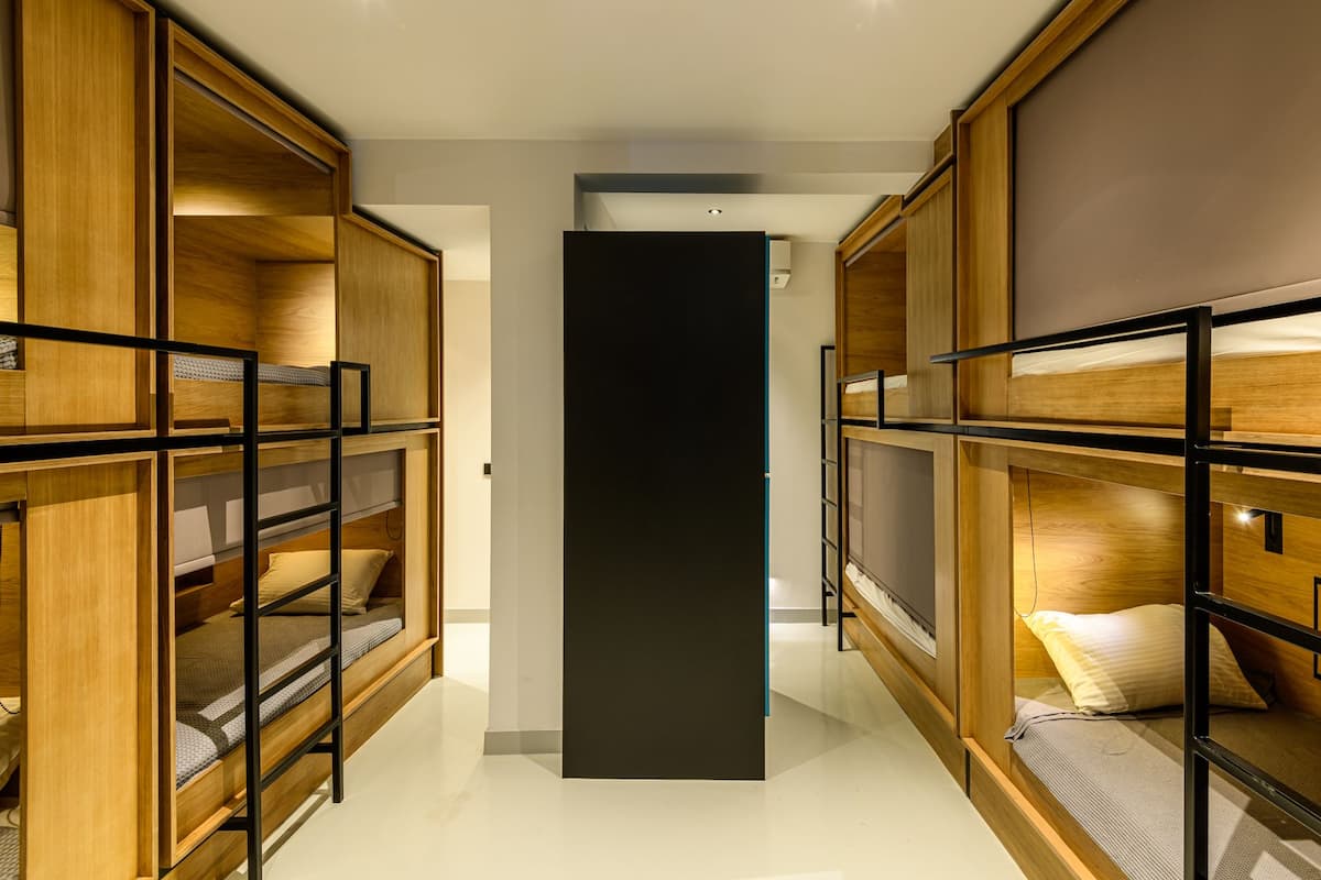 A modern hotel room with bunk beds, wooden paneling, and a central black partition.