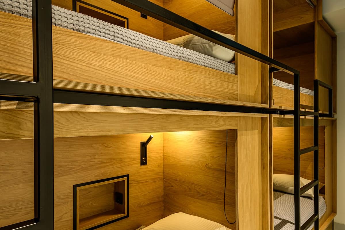 A bunk bed room with wooden walls and metal railings.