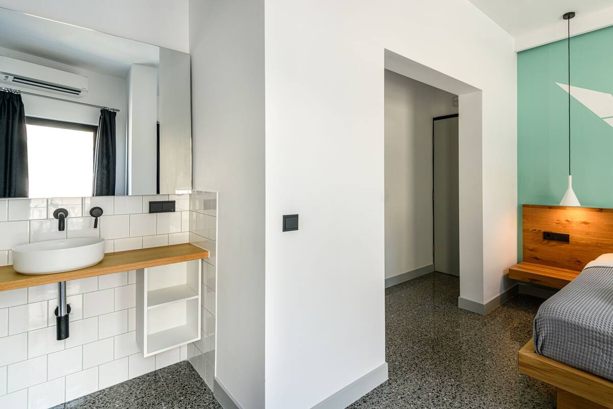 A modern bathroom with a white sink, mirror, and tiled walls.