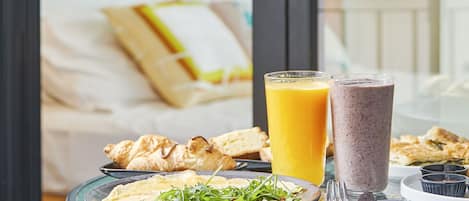 Taula de l'esmorzar amb croissants, un smoothie i un got de suc d'aranja.
