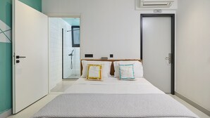 A hotel room with a bed, a bedside table, an air conditioning unit, and a door. - Mosaikon - Hostel (Athens)