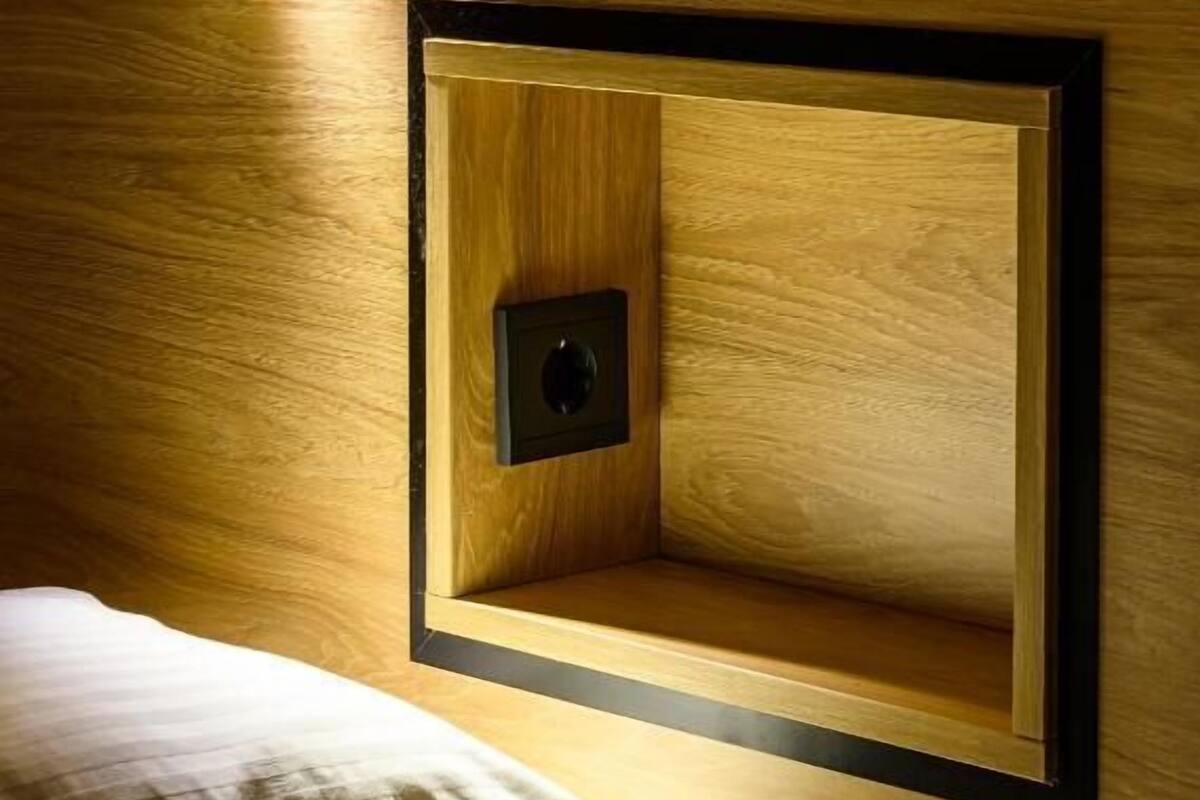 A wooden wall with a recessed shelf and a small black object on it.