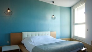 A bedroom with a bed, bedside table, and two pendant lights. - The View (La Marsa)