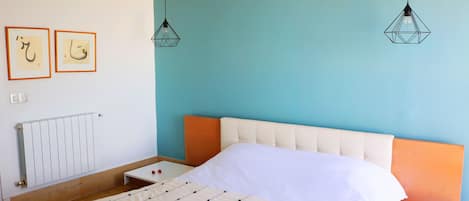 Een slaapkamer met een bed, een nachtkastje, een radiator en twee wandlampen.