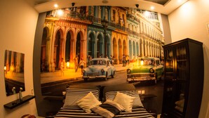 A bed with striped bedding, a nightstand, a small table, and a cabinet.