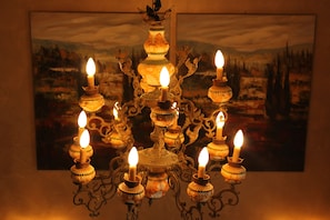 Un lustre orné de nombreuses bougies, placé devant un tableau représentant un paysage.