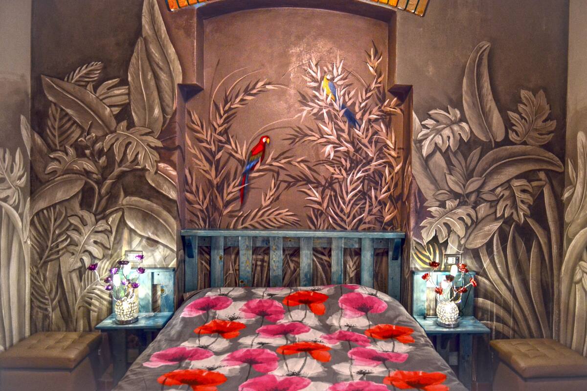 Une chambre avec un lit, deux tables de chevet et une fresque murale.
