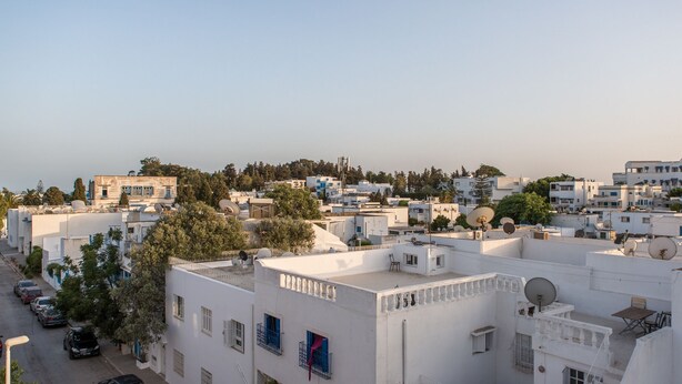 A residential area with white buildings, satellite dishes, and a clear sky. - Didona Triplex (Sidi Bou Said)