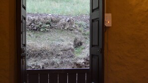 An open door leading to a grassy area, with a light fixture on the wall.