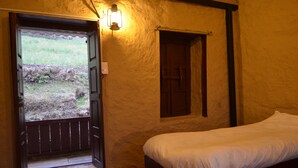 A room with a bed, a window, and a door leading outside.