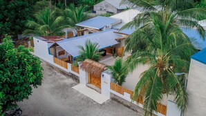 Resort tropical com estrutura de telhado de palha, área de estar coberta ao ar livre e vegetação exuberante.