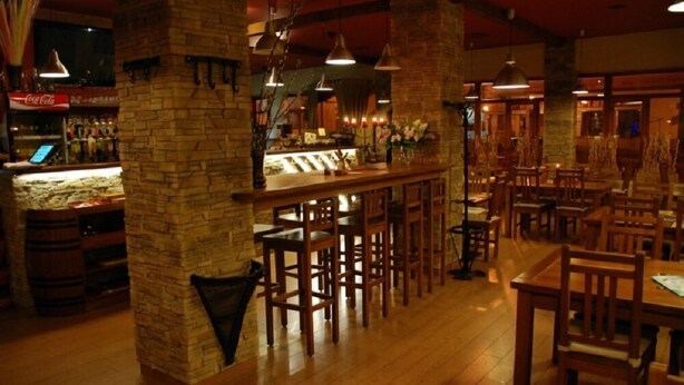 A bar area with wooden stools, a counter with a Coca-Cola sign, and brick walls. - Penzion Longus (Kyjov)