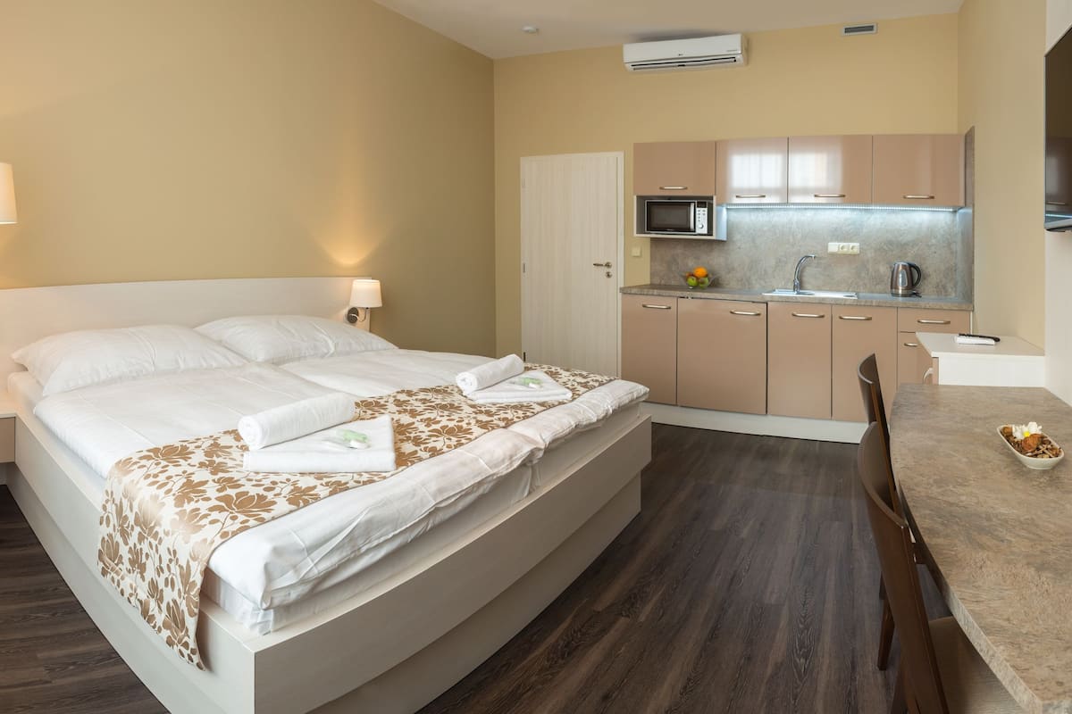 A hotel room with a bed, bedside lamp, and a kitchenette with a microwave and sink.