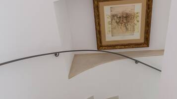 A spiral staircase with a handrail and a framed artwork above it.