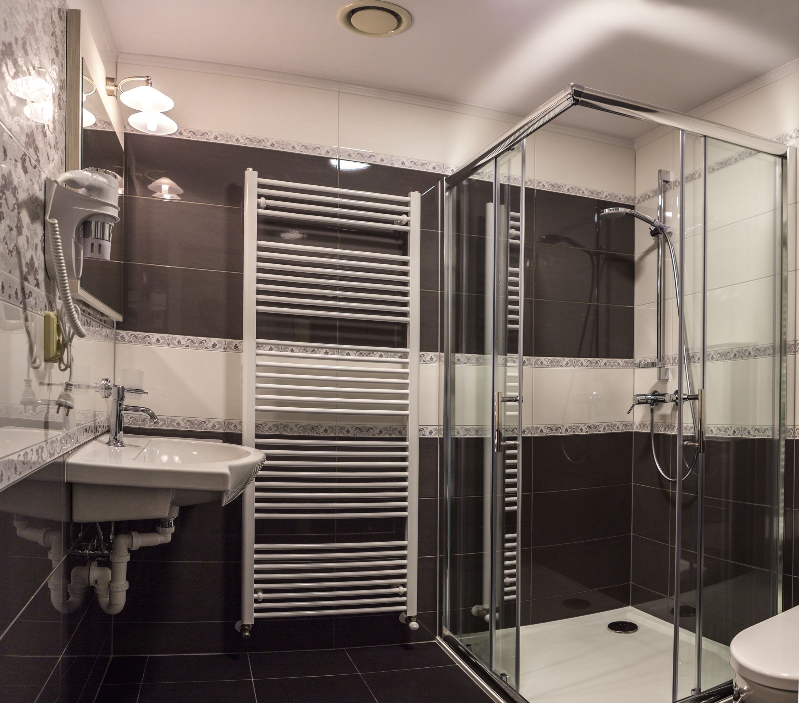 A modern bathroom with a glass-enclosed shower, a white sink, and a towel rack.