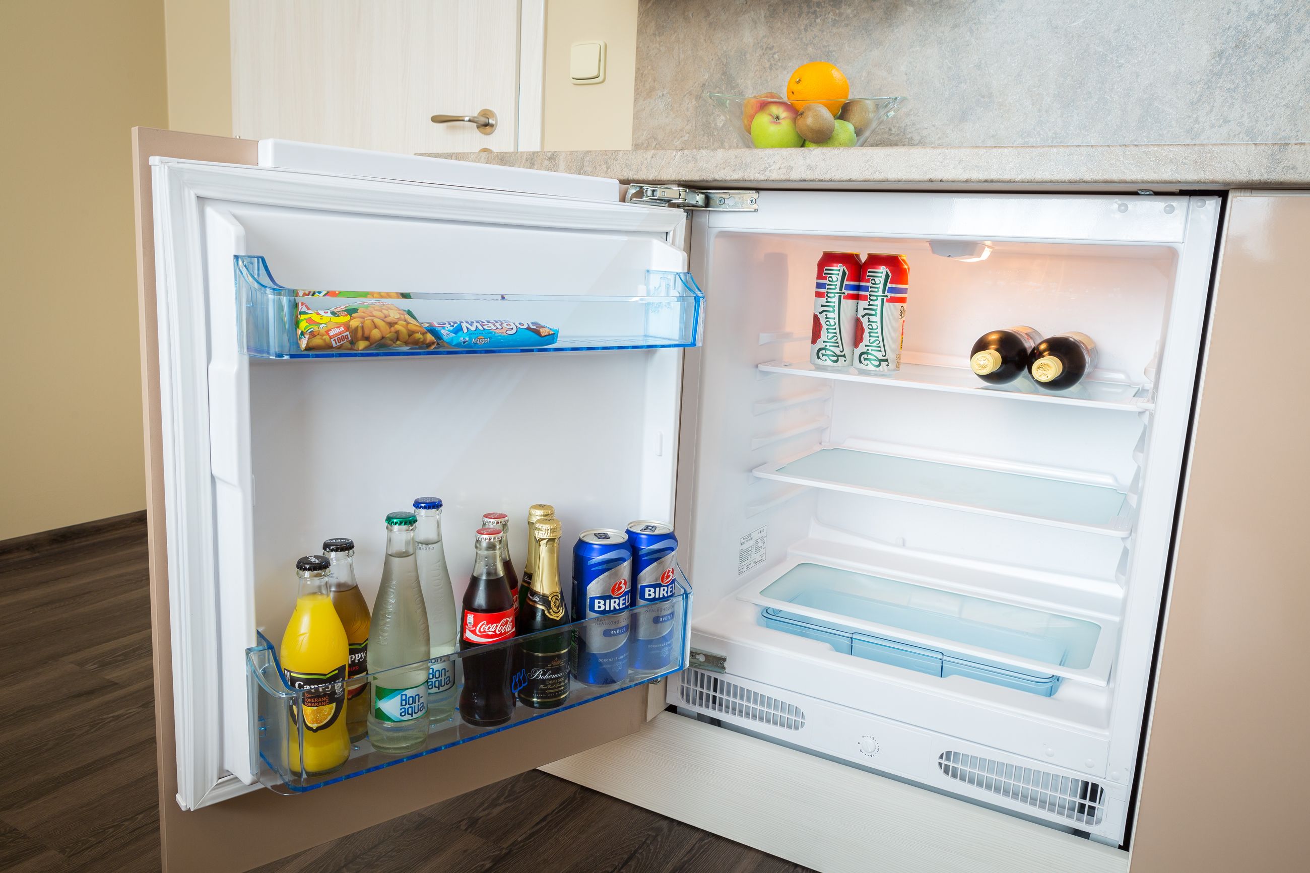 Ein offener Kühlschrank mit Regalen voller Getränke und Snacks.
