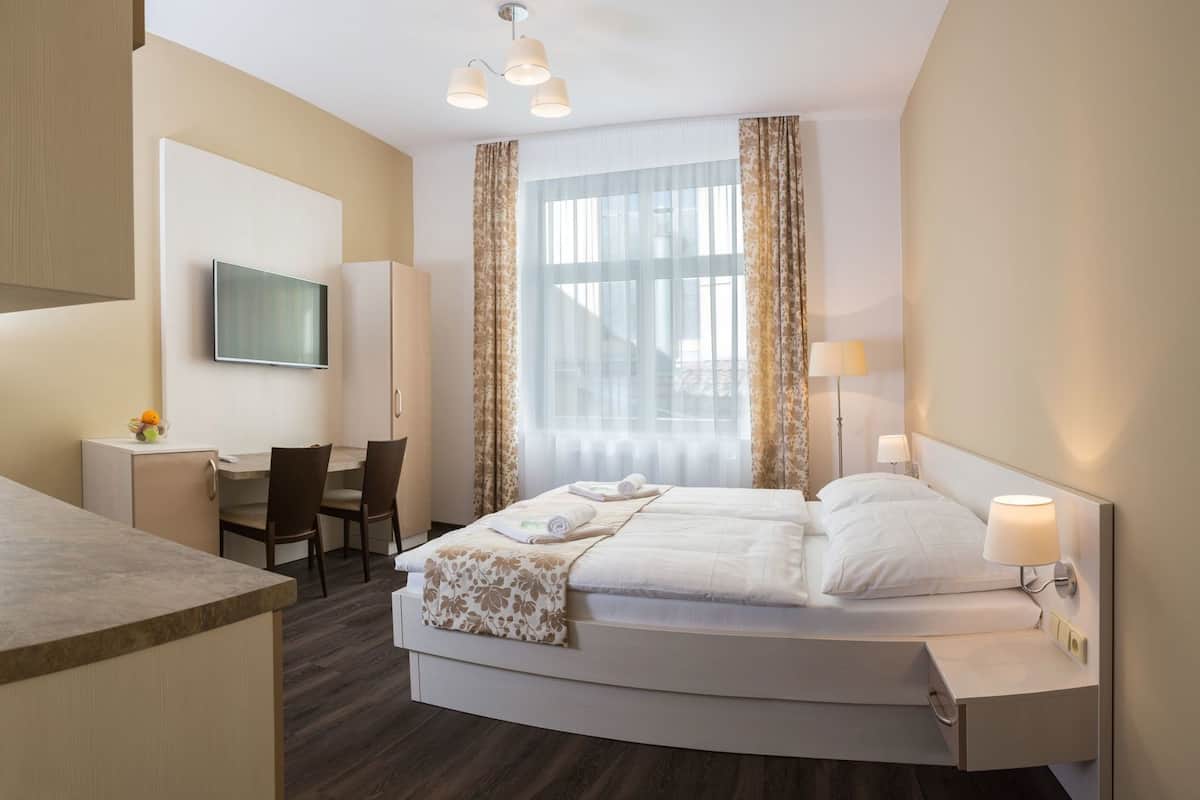 A hotel room with a bed, desk, chair, TV, and curtains.