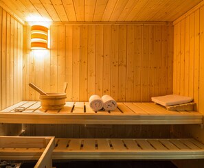 A wooden sauna with benches, a wooden bucket, and rolled towels. - Penzion Longus (Kyjov)