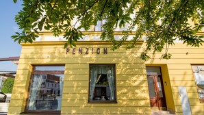 A yellow building with the name "PENZION" on the facade, large windows, and a door. - Penzion Longus (Kyjov)