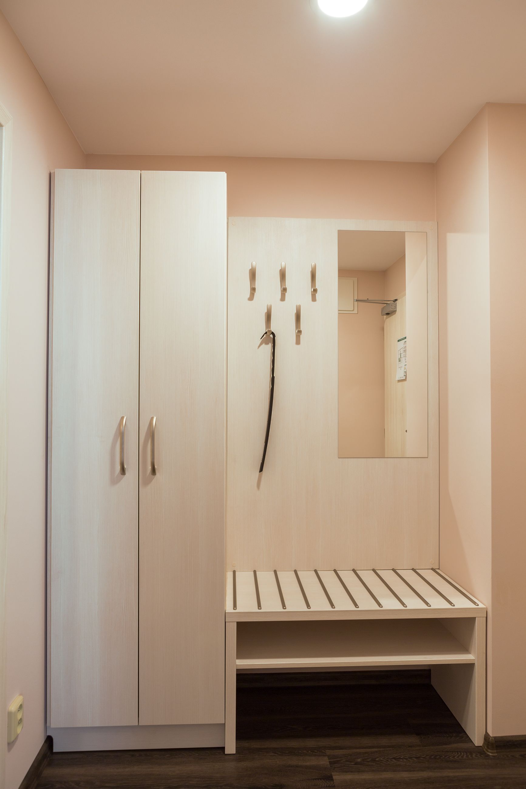 A room with a wardrobe, a mirror, and a bench.