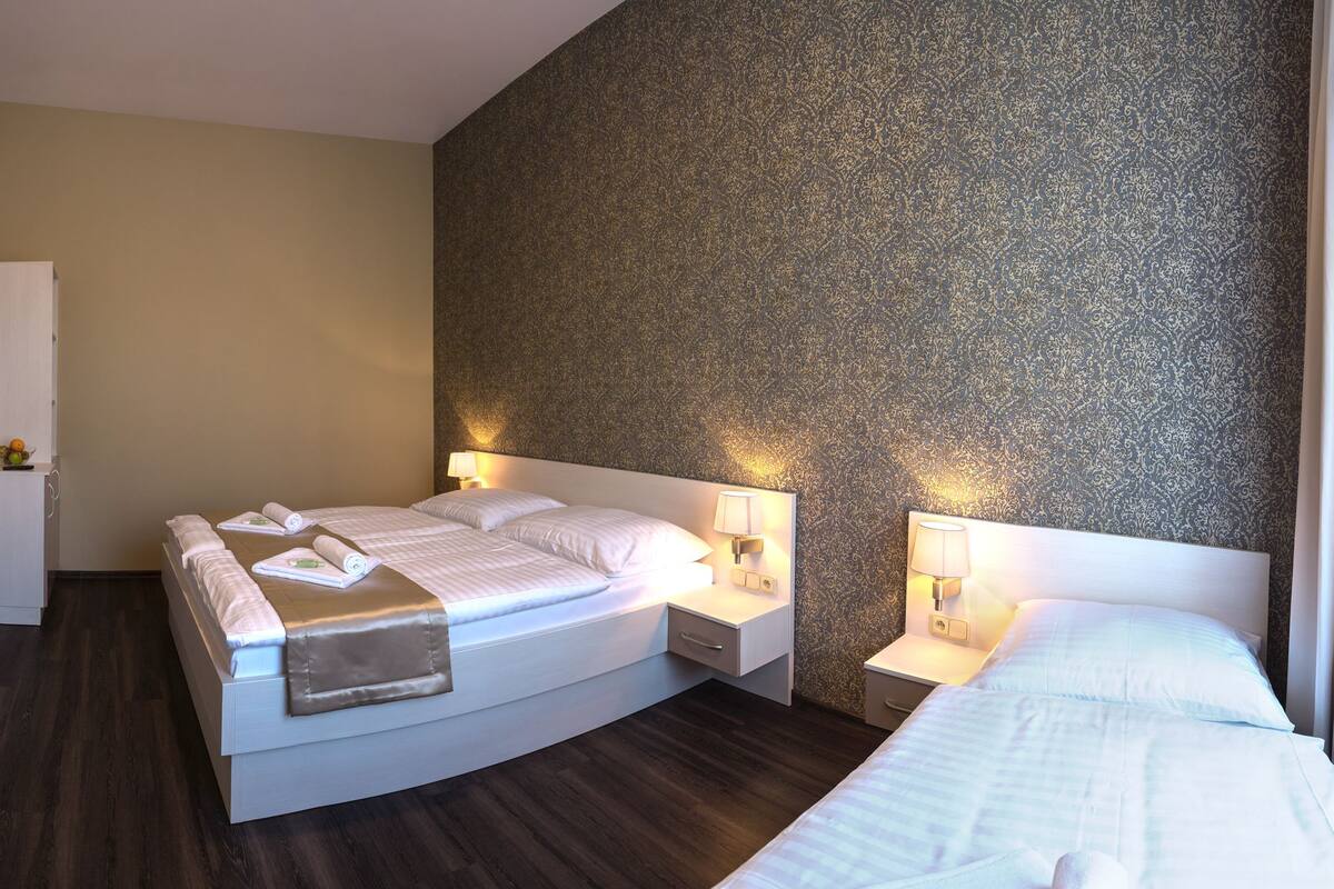 A hotel room with a large bed, bedside tables with lamps, a flat-screen TV, and a wardrobe.