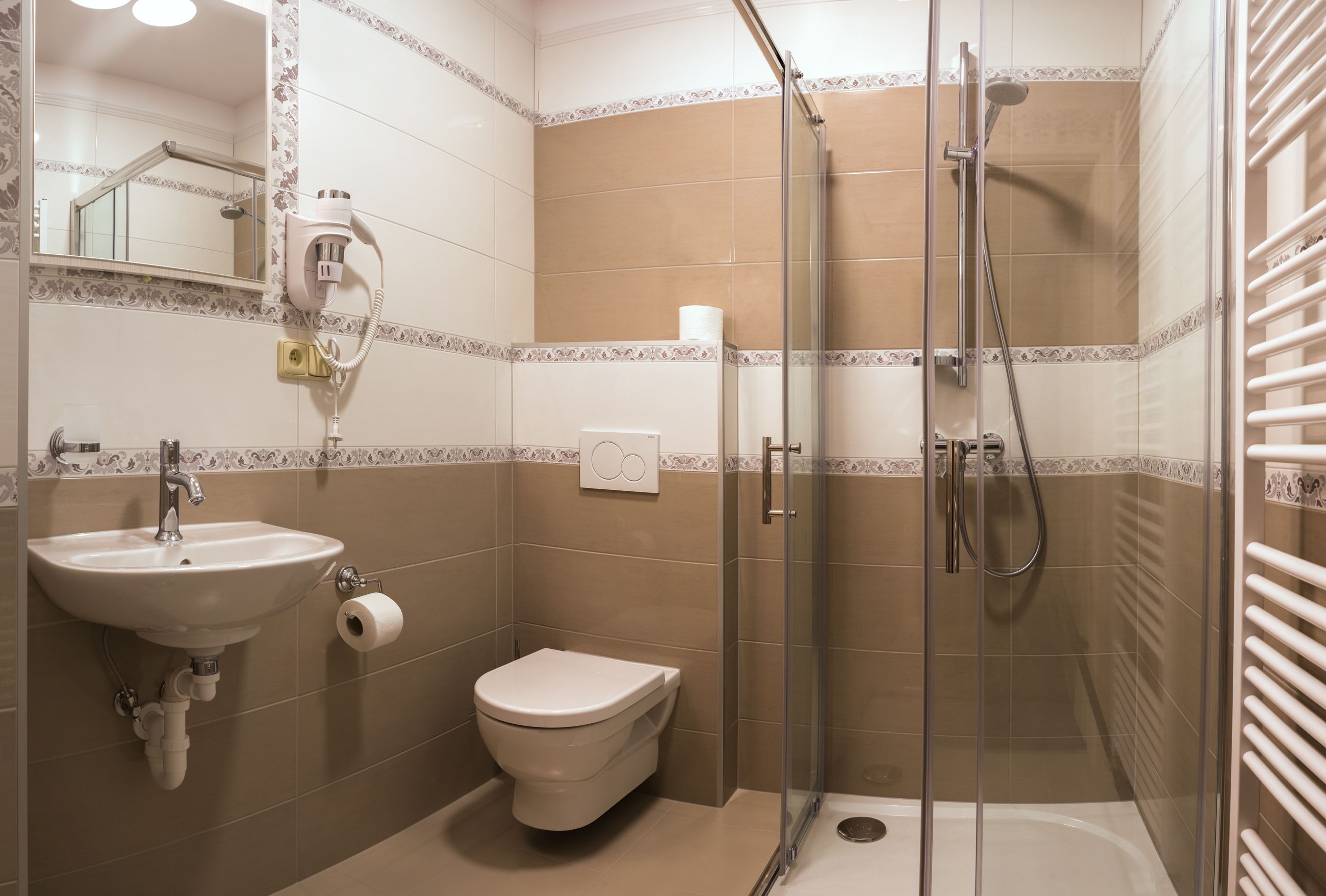 Un baño con lavamanos, inodoro y cabina de ducha con mampara de vidrio.