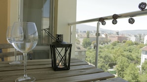 A balcony with a wooden table, a glass of water, and a lantern. - Cozy apARTment (Sofia)
