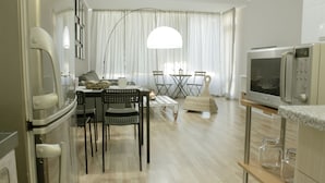A modern kitchen with a dining area, a large window with sheer curtains, and a flat-screen TV. - Cozy apARTment (Sofia)