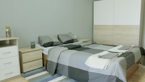 A bedroom with a bed, nightstands, a dresser, and a wooden headboard. - Cozy apARTment (Sofia)