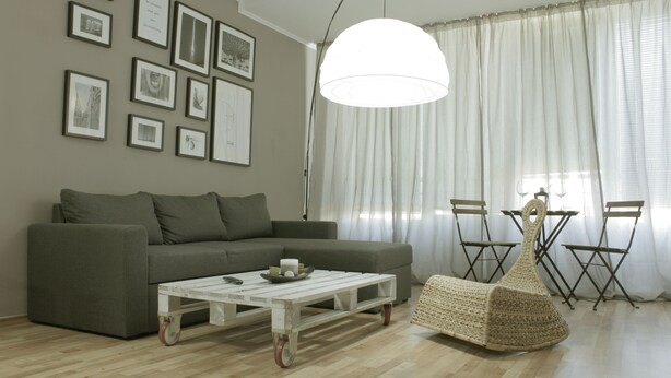 A living room with a grey sofa, a white coffee table, and a woven pouf. There are framed pictures on the wall and a large white lamp. - Cozy apARTment (Sofia)