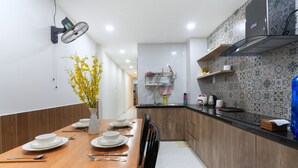 A modern kitchen with a wooden dining table set for four, a built-in oven, and a patterned backsplash.