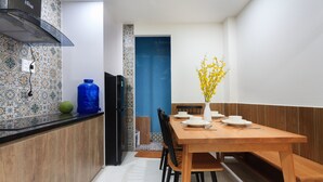 A modern kitchen with a wooden dining table, black chairs, and a blue water dispenser.