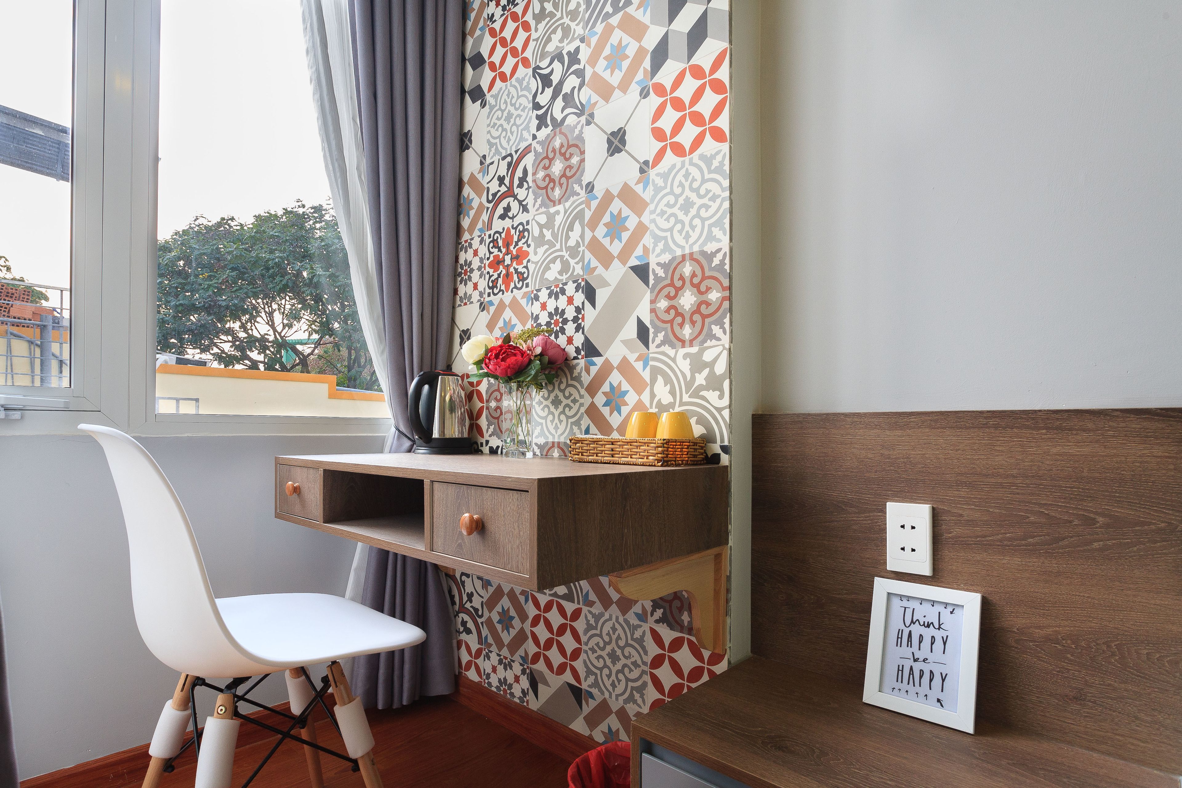A small room with a white chair, a wooden desk, a patterned wall, and a motivational quote on the wall.